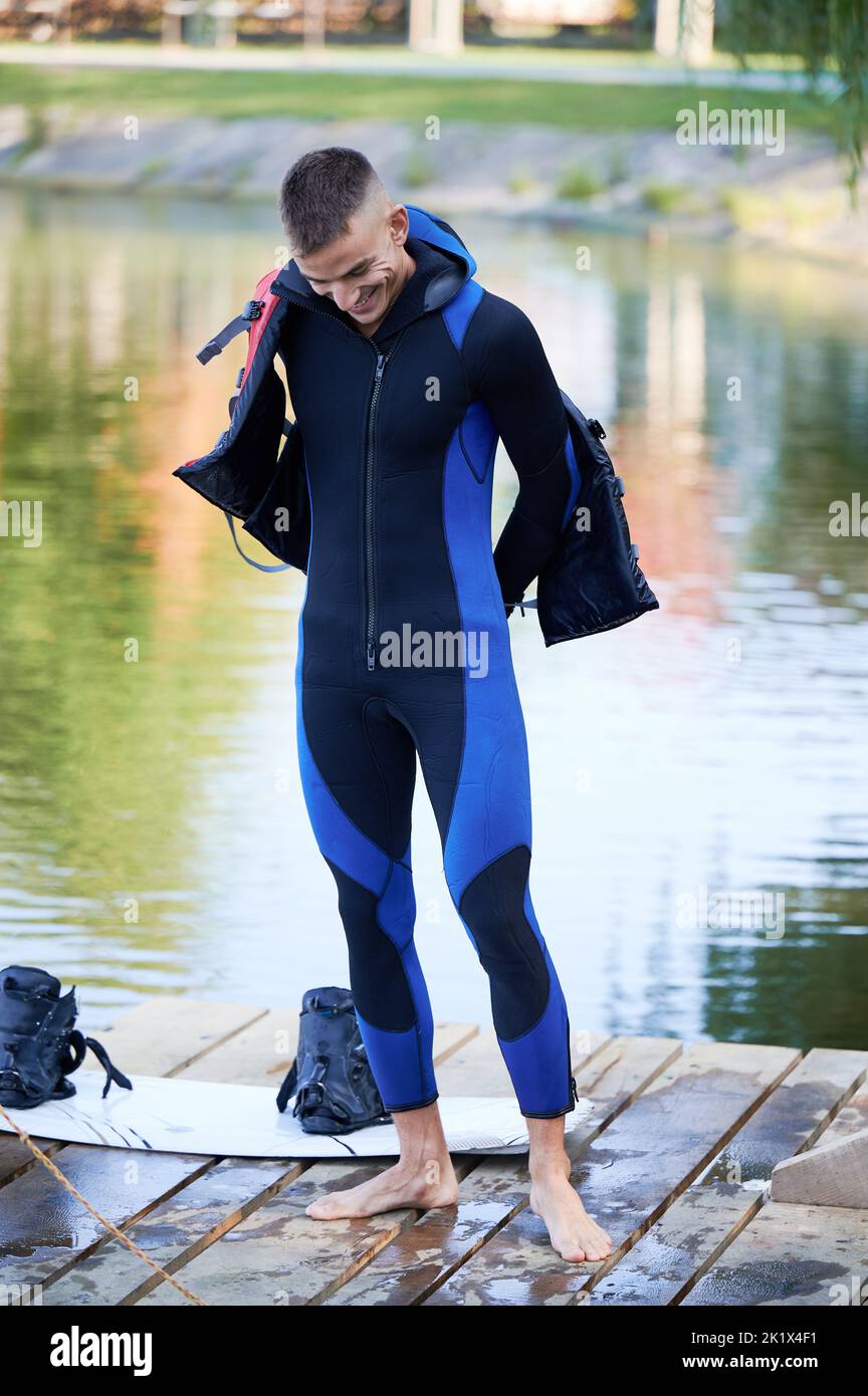 Wakeboarder making ready of surfing on lake. Young surfer wearing wetsuit of wakeboarding in the cable park. Water sport, outdoor activity concept. Stock Photo