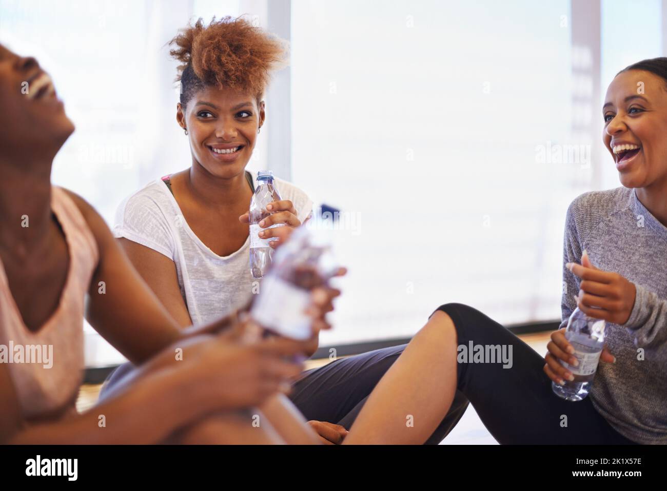 Bonding during their break. a group of happy young dancers sitting on the floor of their dance studio. Stock Photo