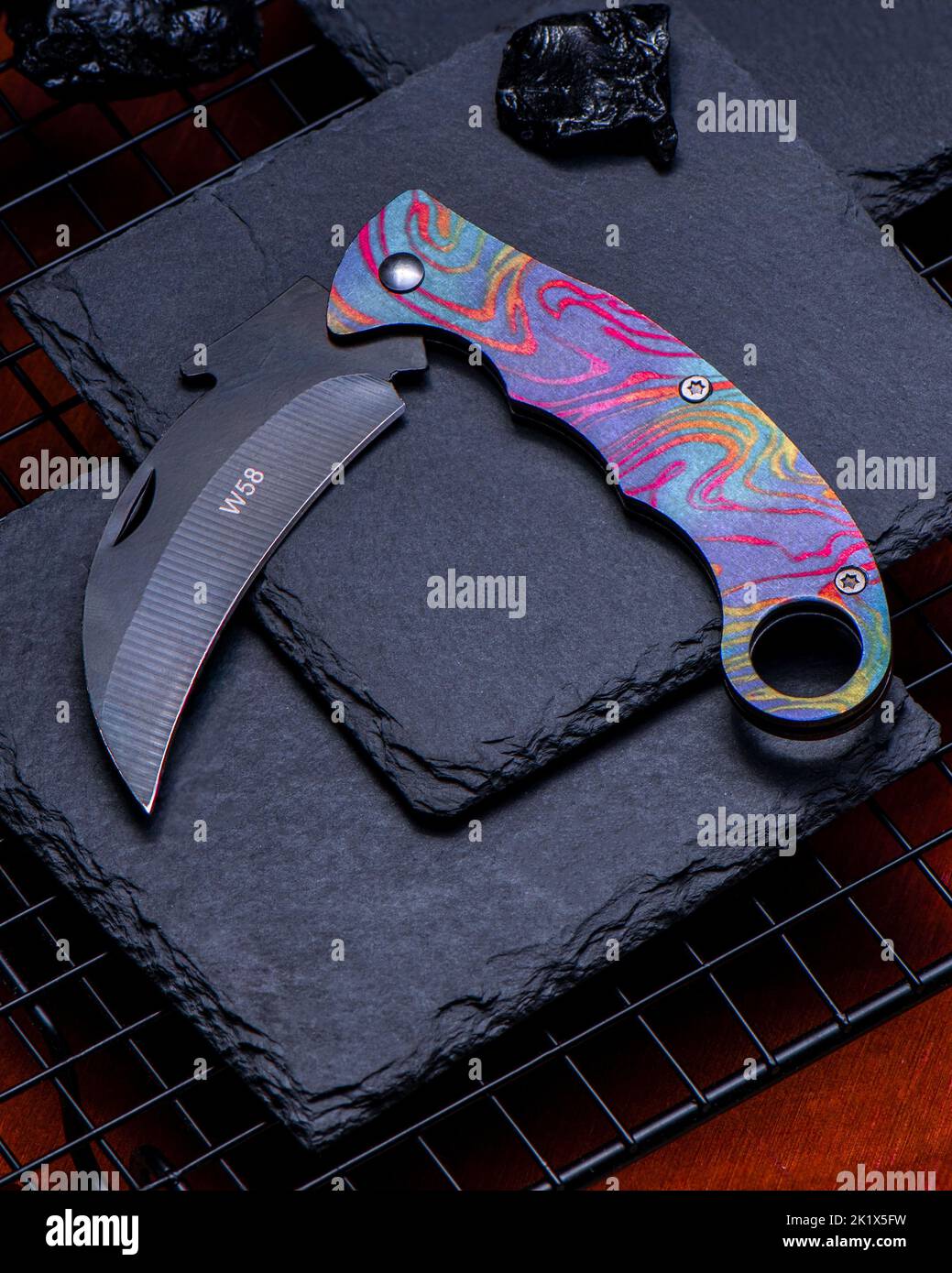 A closeup shot of a beautiful pocket knife with an abstract colorful design on the handle Stock Photo
