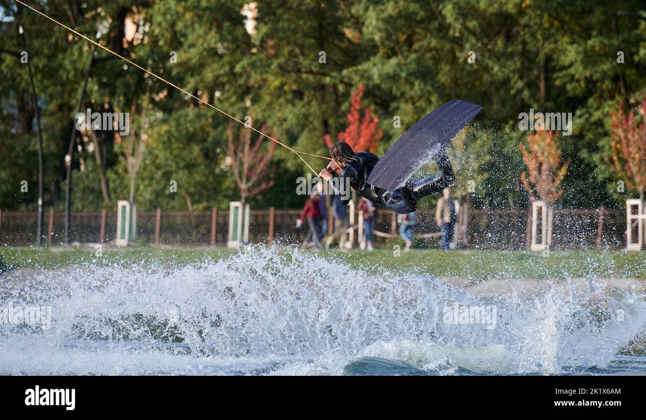 Wakeboarder making tricks while wakeboarding on lake. Young man surfer having fun wakesurfing in