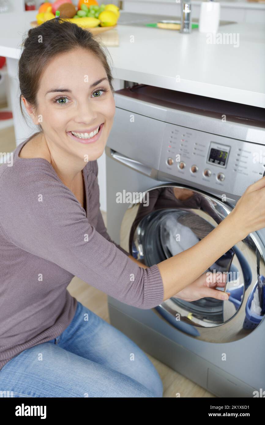 closeup of woman hand loading dirty clothes in washing machine Stock