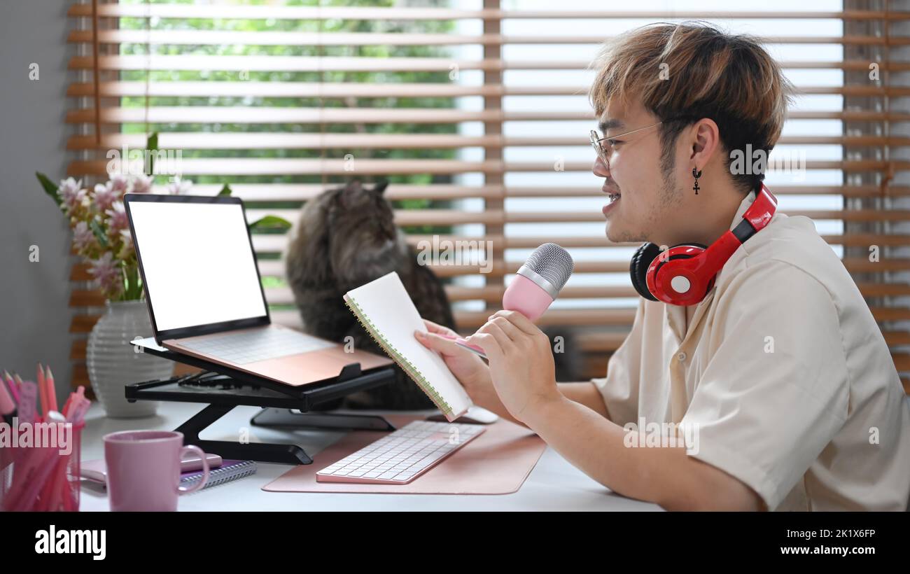 Young podcaster using a microphone and laptop computer recording audio