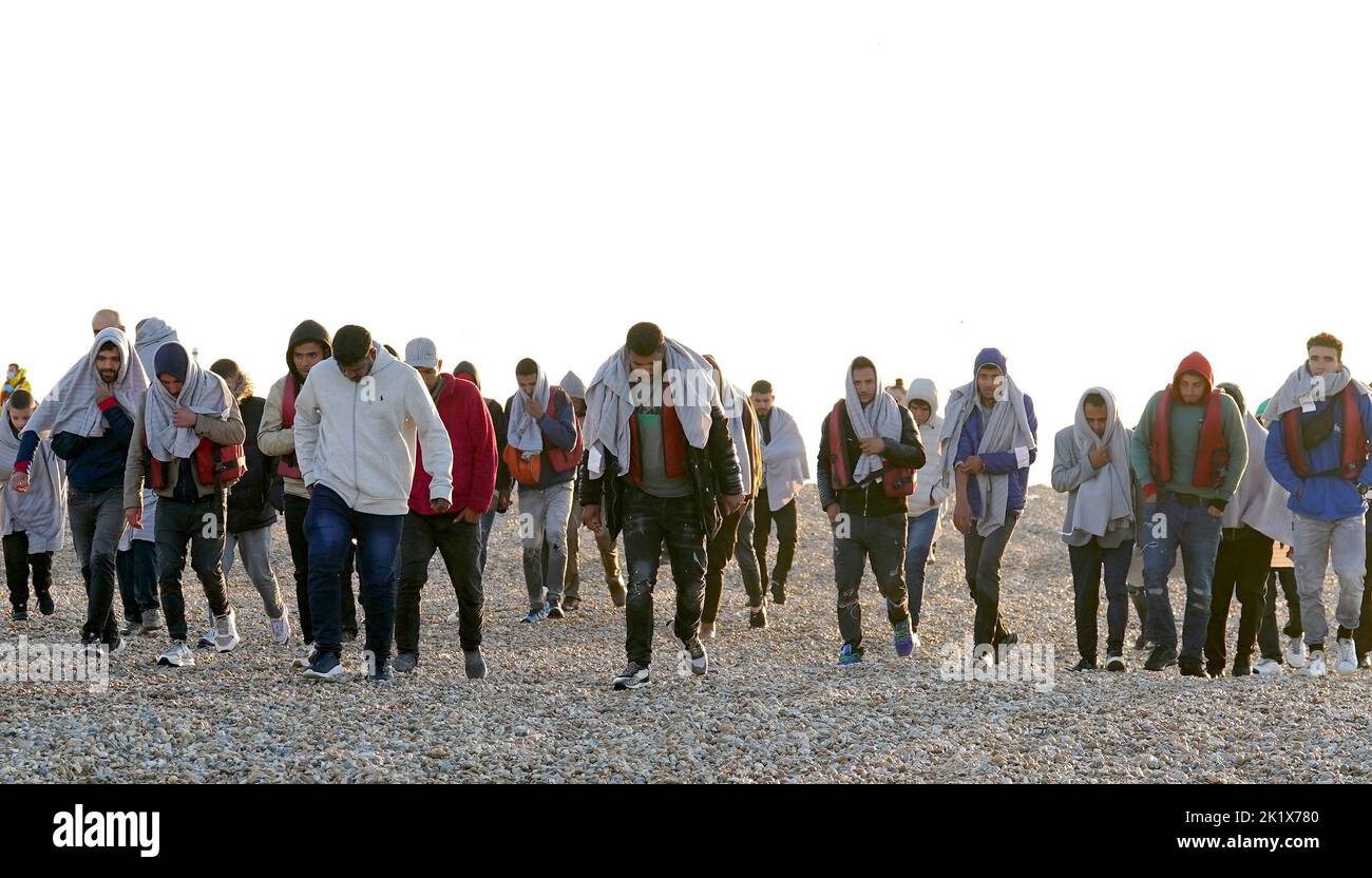 A group of people thought to be migrants walk up the beach in Dungeness, Kent, after being rescued in the Channel by the RNLI following following a small boat incident. Picture date: Wednesday September 21, 2022. Stock Photo