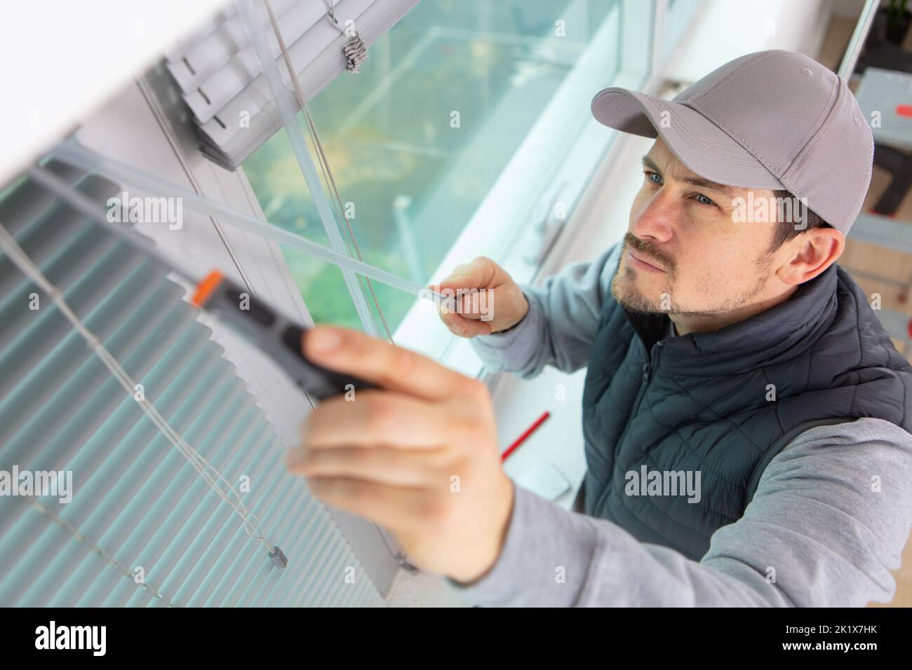 construction worker man install blinds on plastic white upvc windows Stock Photo