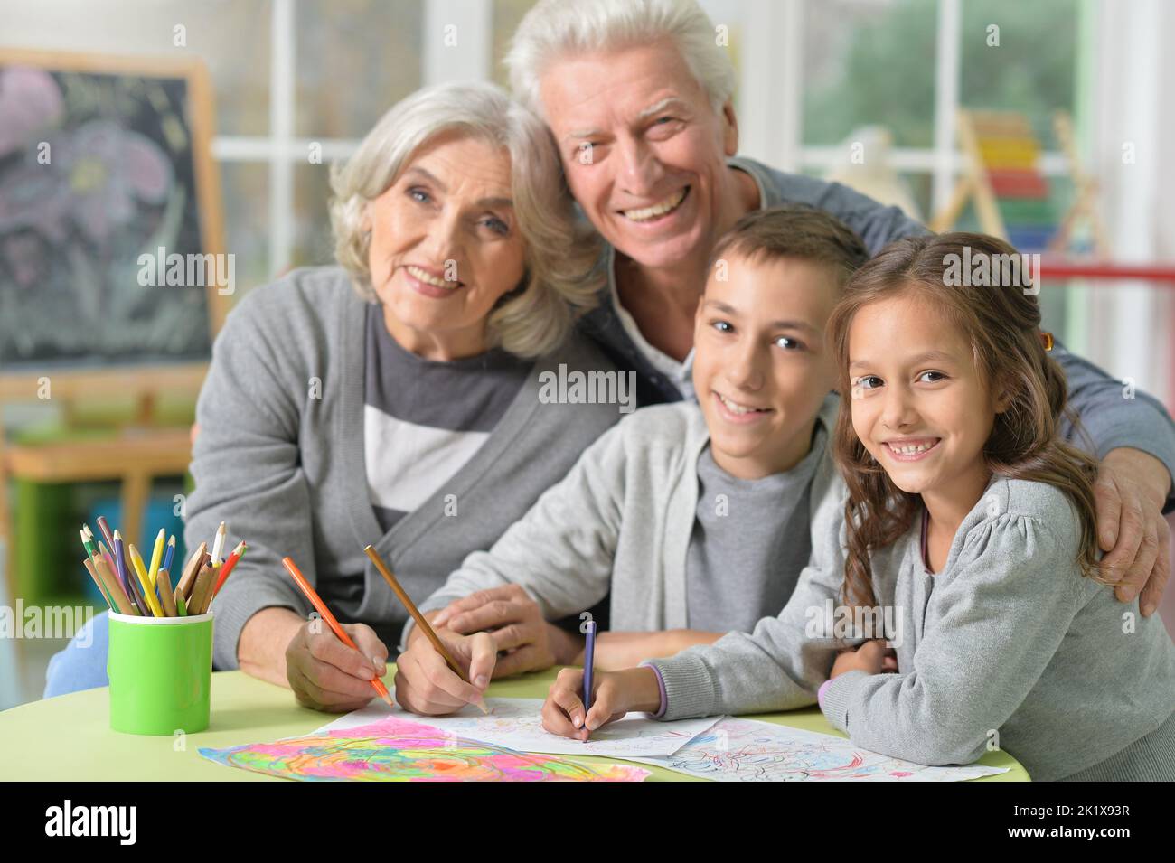 Portrait of grandparents and grandchildren drawing at home Stock Photo