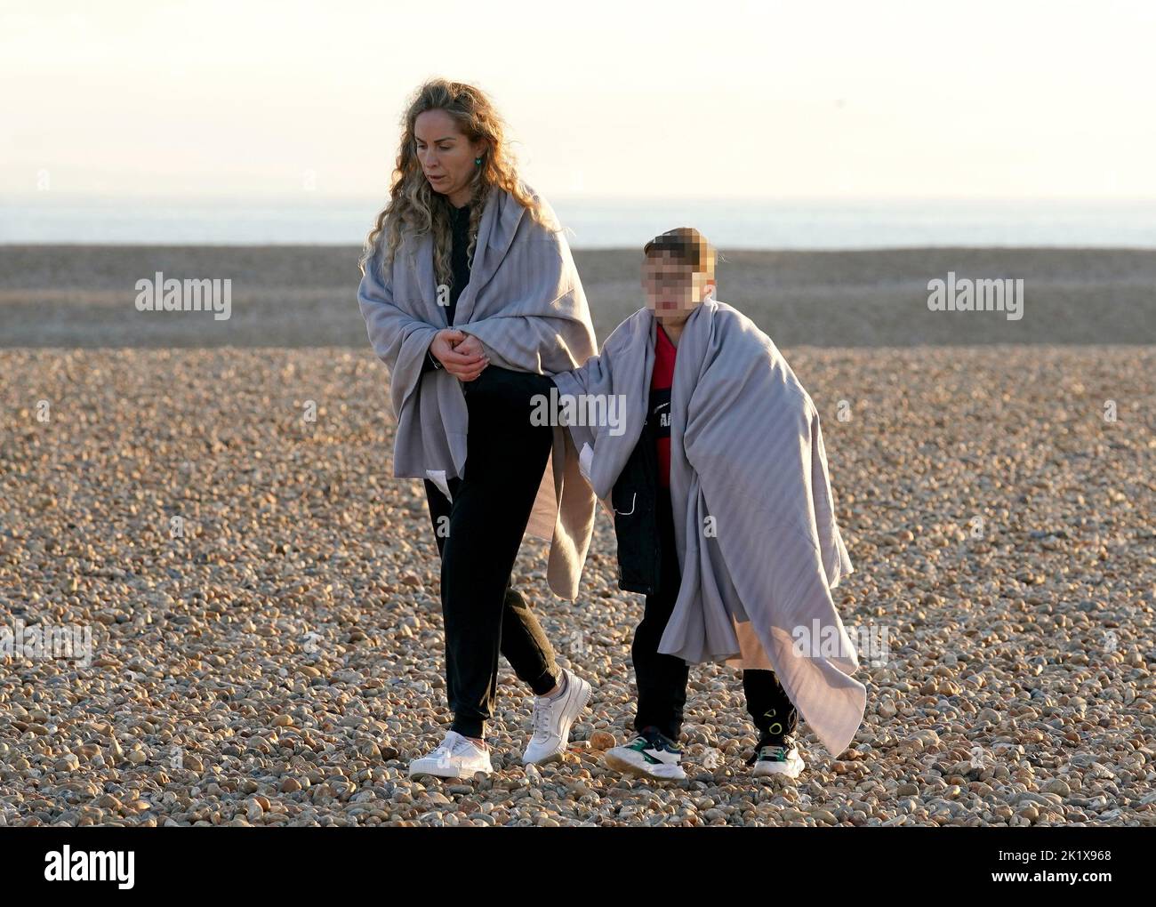 EDITORS NOTE Children's faces have been pixelated as the PA Picture Desk has been unable to gain the necessary permission to photograph a child under 16 on issues involving their welfare. A woman and young boy amongst a group of people thought to be migrants as they walk up the beach in Dungeness, Kent, after being rescued in the Channel by the RNLI following following a small boat incident. Picture date: Wednesday September 21, 2022. Stock Photo