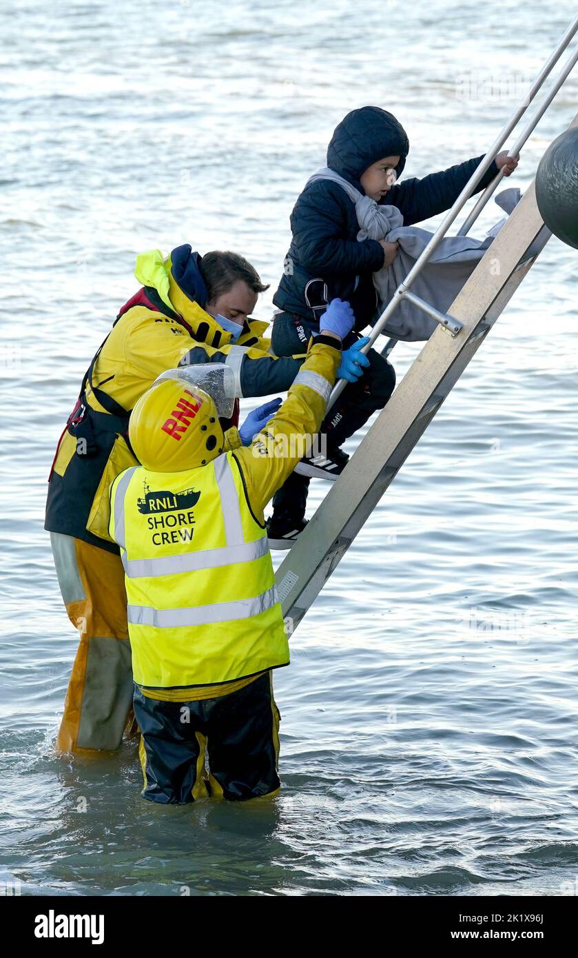 EDITORS NOTE: The PA Picture Desk has been unable to gain the necessary permission to photograph children under 16 on issues involving their welfare. This image has been provided unpixelated for customers to pixelate in their own style. A young child is helped to shore in Dungeness, Kent, after being rescued in the Channel by the RNLI following following a small boat incident. Picture date: Wednesday September 21, 2022. Stock Photo