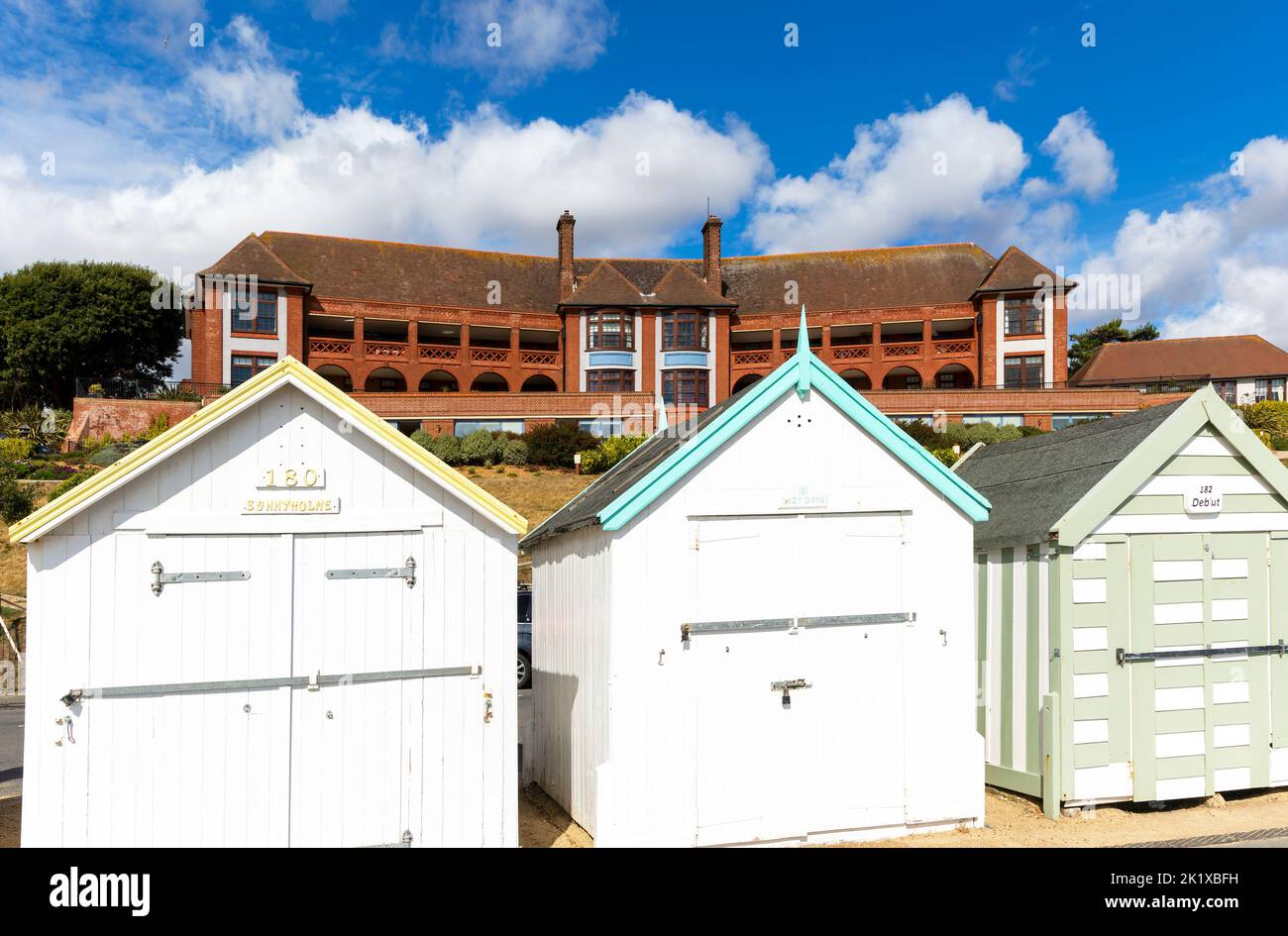 Colourful beach huts on seafront, Barlet Hospital building behind, Felixstowe, Suffolk,  England, UK Stock Photo