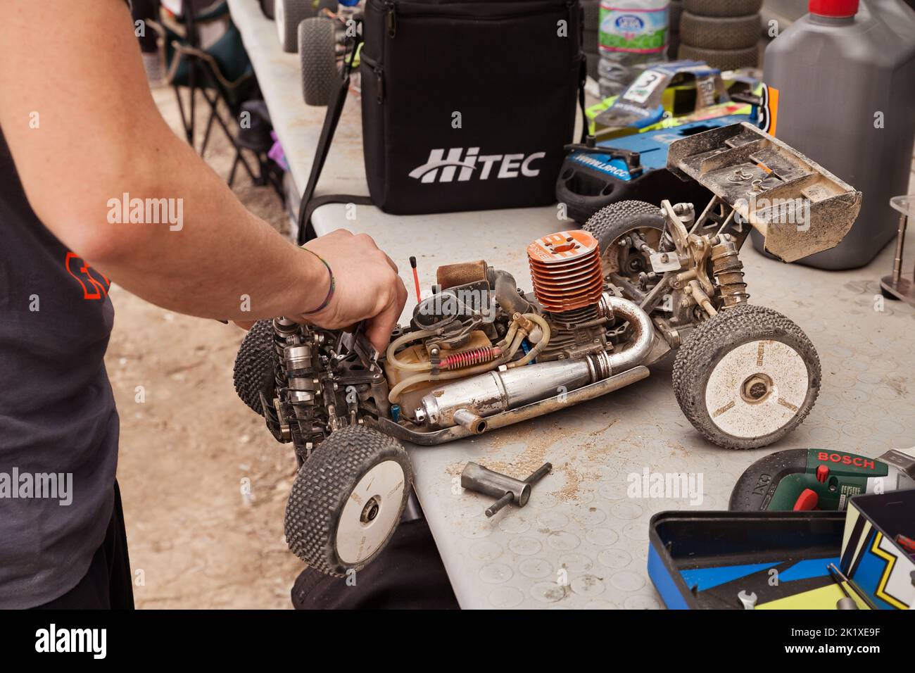 man working on the radio controlled buggy car model, internal combustion engine, during the regional championship scale 1/8 off road in dirt track Il Stock Photo