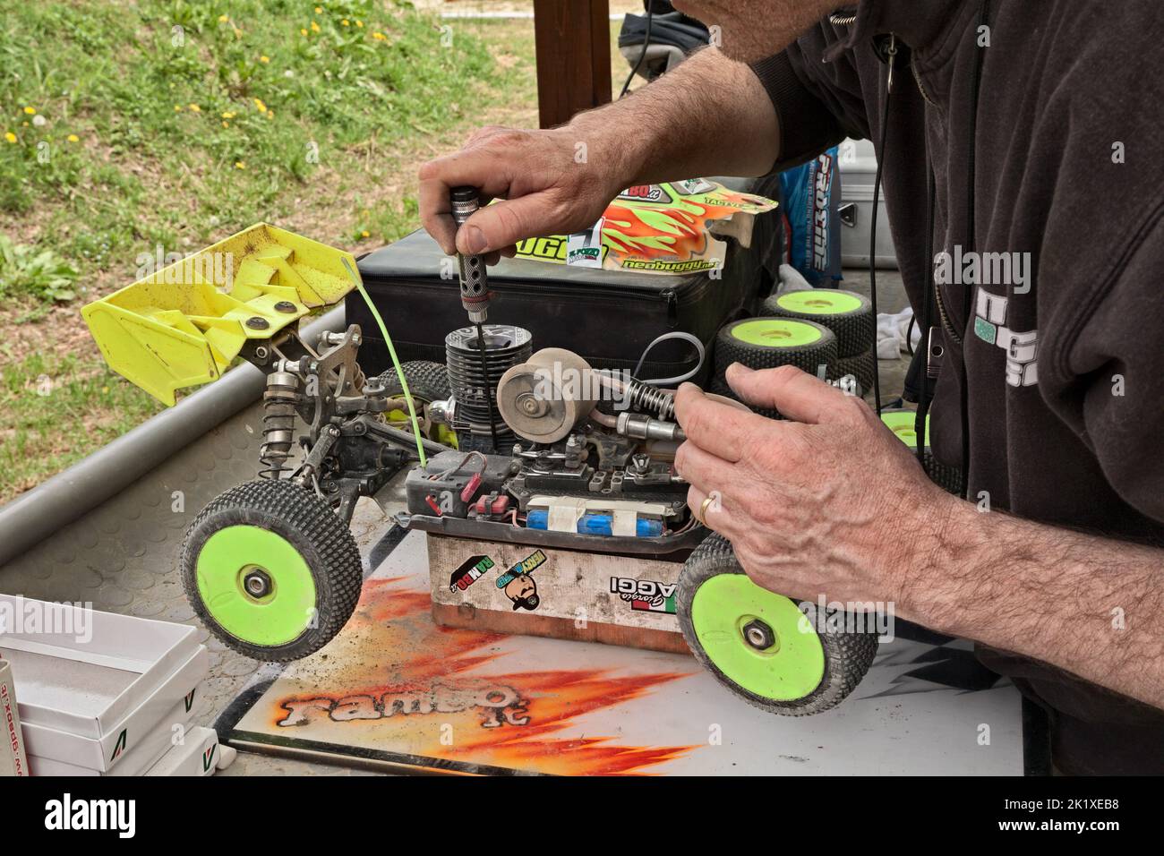man working on the radio controlled buggy car model, internal combustion engine, during the regional championship scale 1/8 off road in dirt track Il Stock Photo