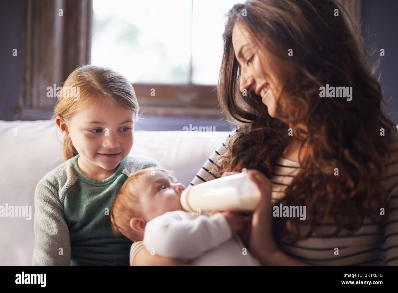 She loves her little sister. A shot of a family spending time together while mom nurses baby. Stock Photo