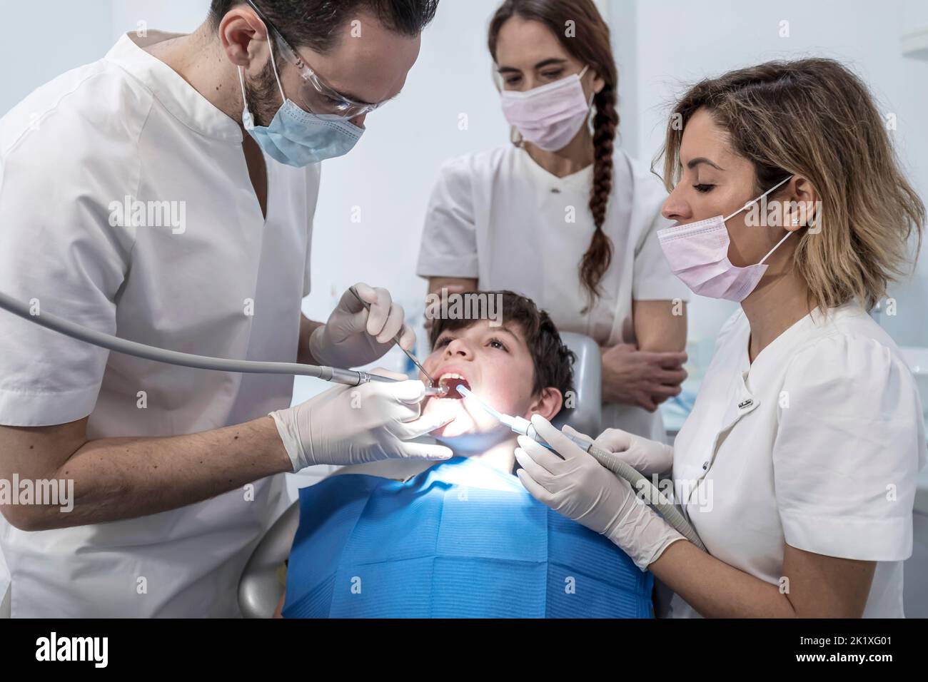 Male dentist with assistants examining boy teeth in the dentists chair