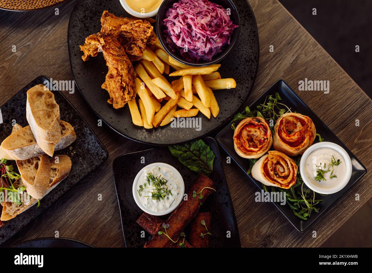 Ciabatta plate, vegetables on plate and roasted grill chicken, french fries, beet root salad, meat rolls. Table layout Stock Photo