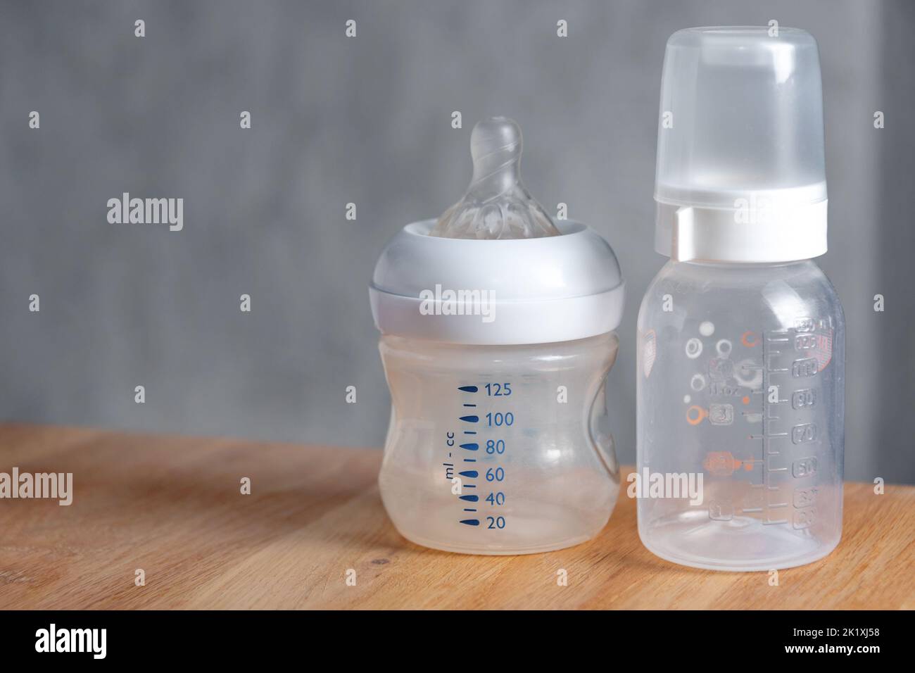 Nursing bottles for newborn baby on wooden table. Preparing milk for baby feeding. Empty space for text. Stock Photo