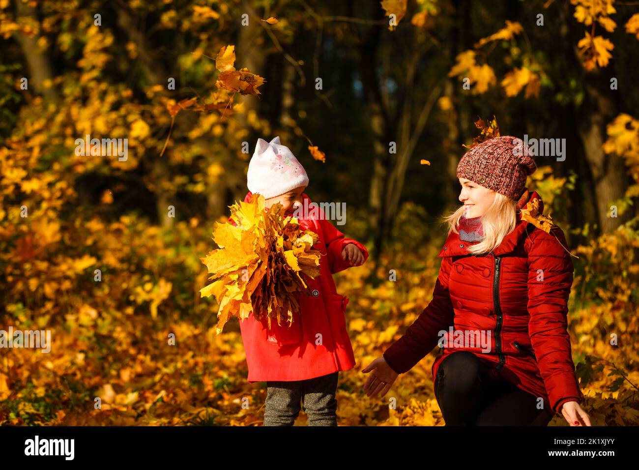 Mother and daughter having fun in the autumn park among the falling ...