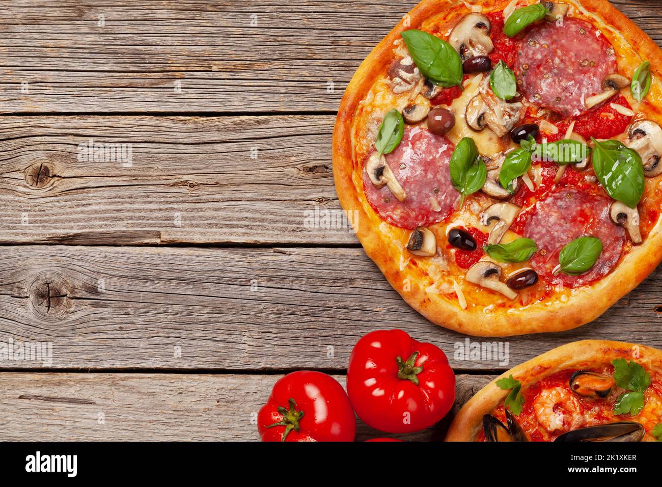 Italian cuisine. Pepperoni and seafood pizza. Flat lay on wooden table with copy space Stock Photo