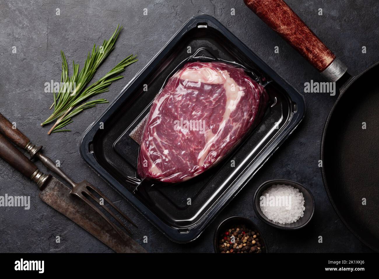 Vacuum packed beef steak. Ribeye steak and cooking utensils. Top view