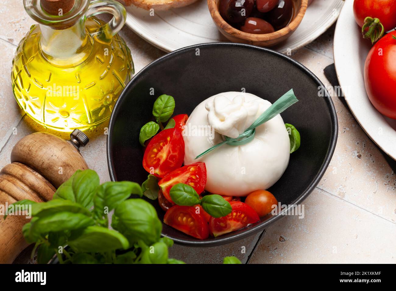 Burrata cheese, various tomatoes and olives. Italian cuisine Stock Photo