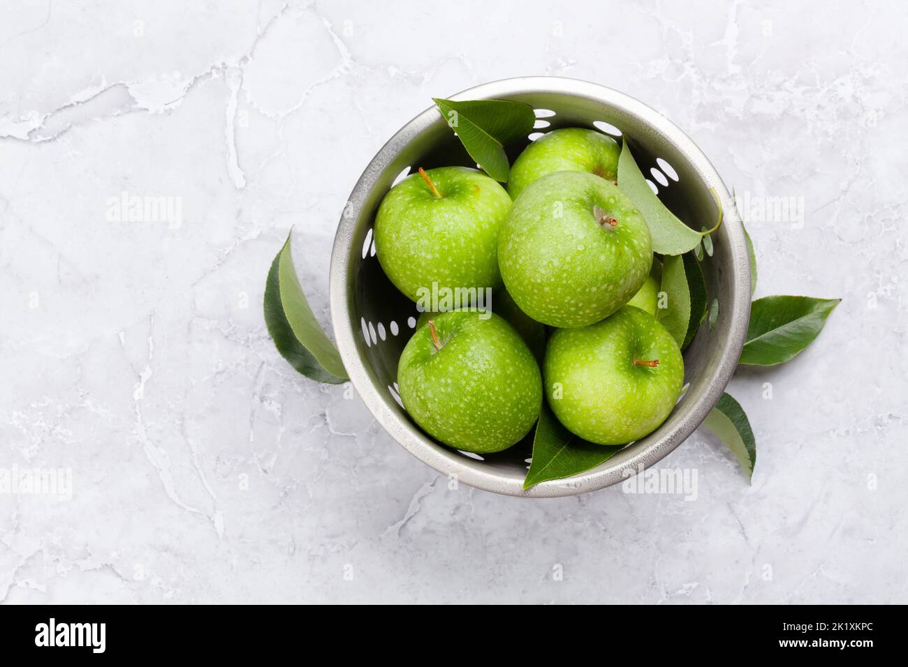 Fresh green apples in colander on stone table. Flat lay with copy space Stock Photo