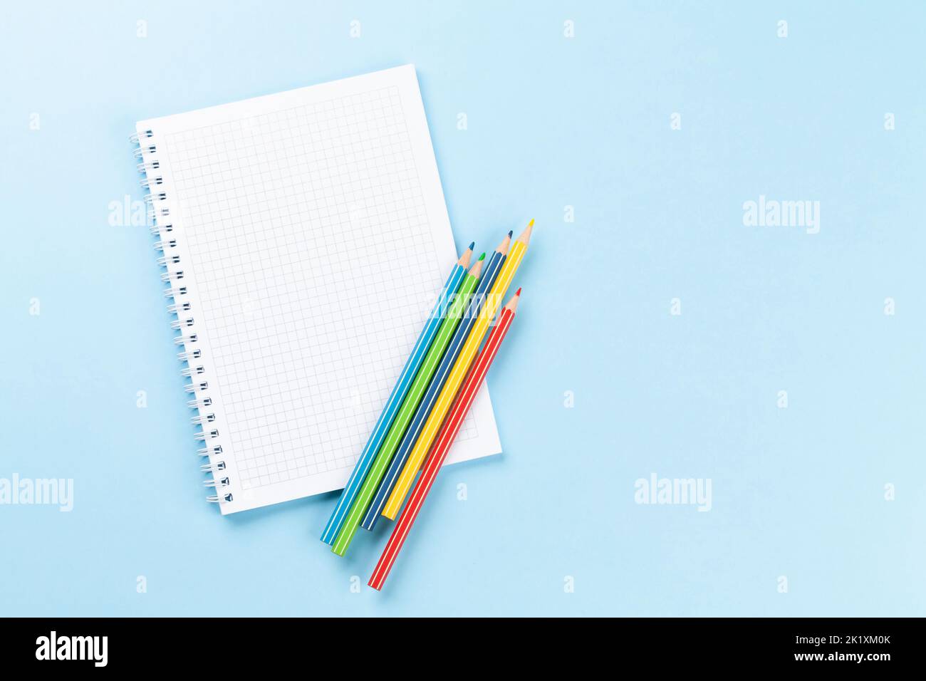 Blank notepad and colorful pencils. Flat lay over blue background with copy space Stock Photo