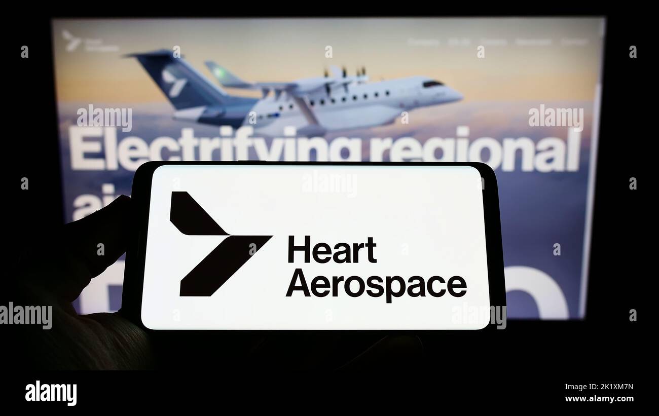Person holding smartphone with logo of Swedish company Heart Aerospace AB on screen in front of website. Focus on phone display. Stock Photo