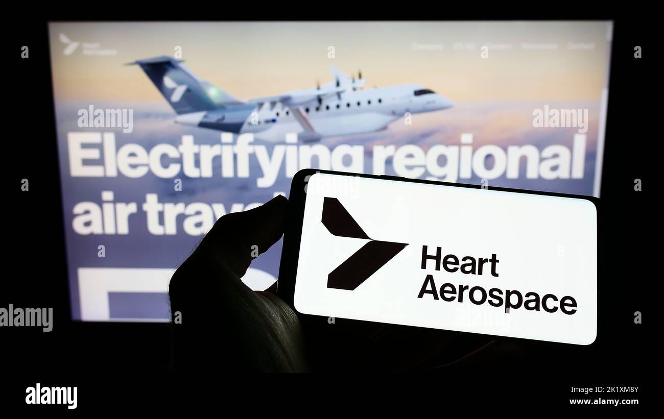 Person holding cellphone with logo of Swedish company Heart Aerospace AB on screen in front of business webpage. Focus on phone display. Stock Photo
