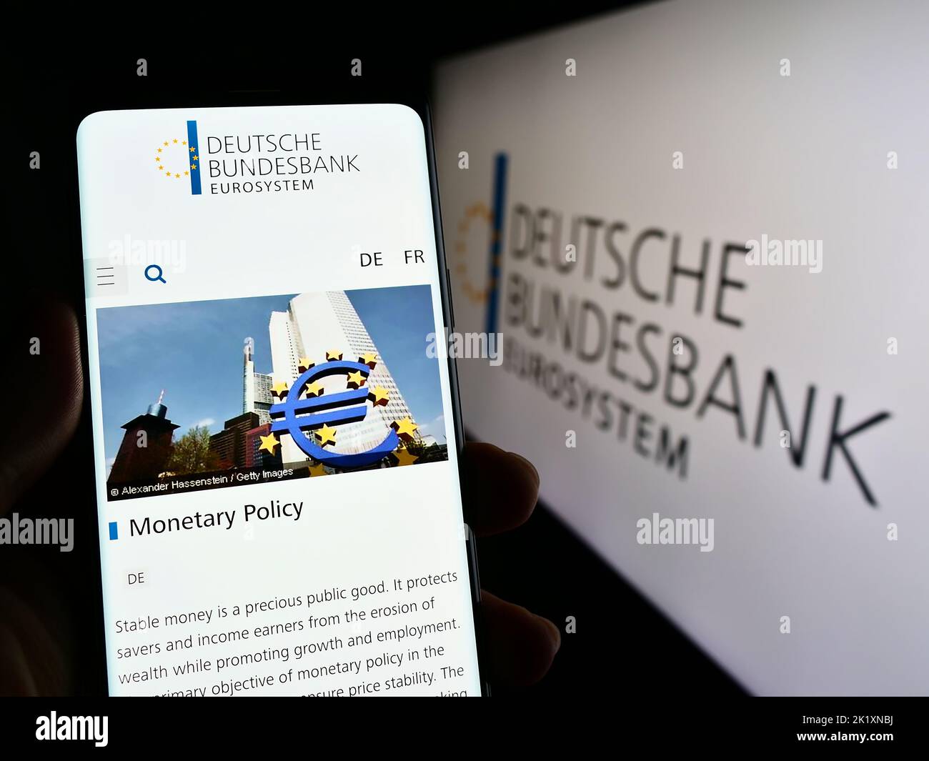 Person holding smartphone with webpage of German central bank Deutsche Bundesbank on screen in front of logo. Focus on center of phone display. Stock Photo