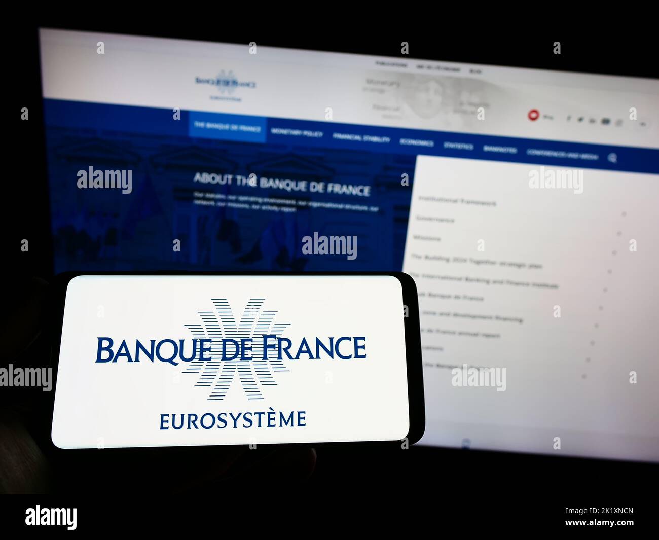 Person holding smartphone with logo of French central bank Banque de France on screen in front of website. Focus on phone display. Stock Photo