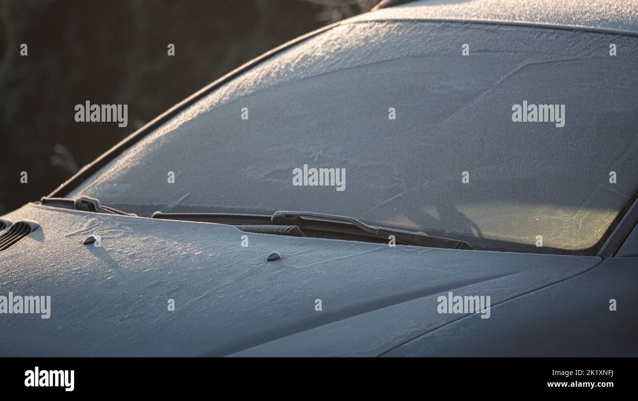 Frost on the car. Frozen car in the rays of the rising sun. Time to scrape the glass. Stock Photo