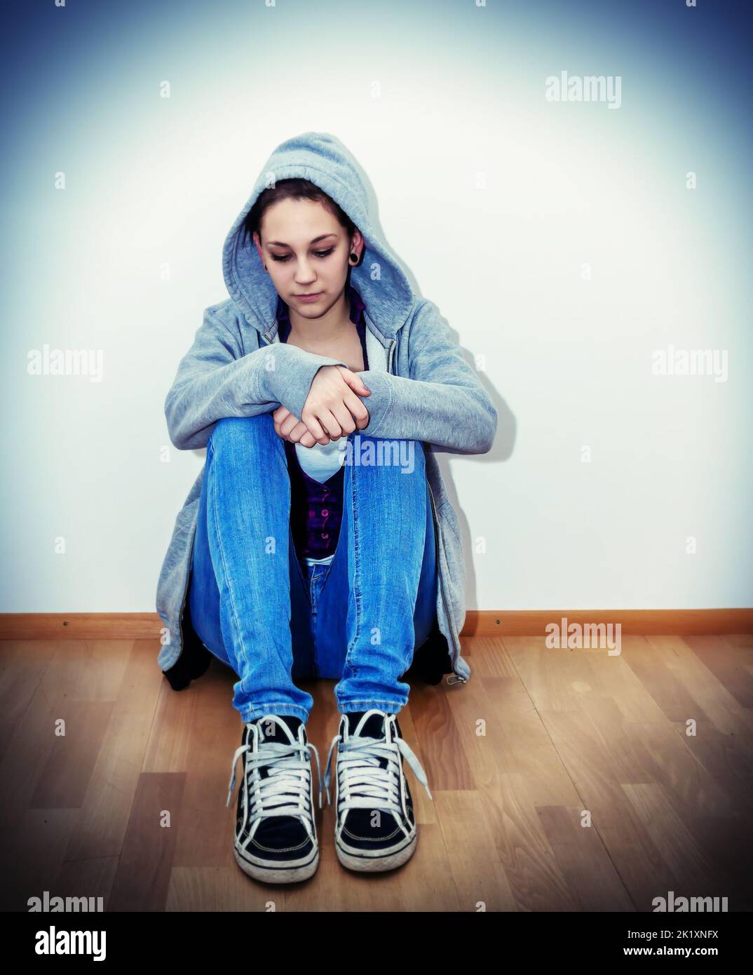 Very sad girl sitting on the floor Stock Photo - Alamy