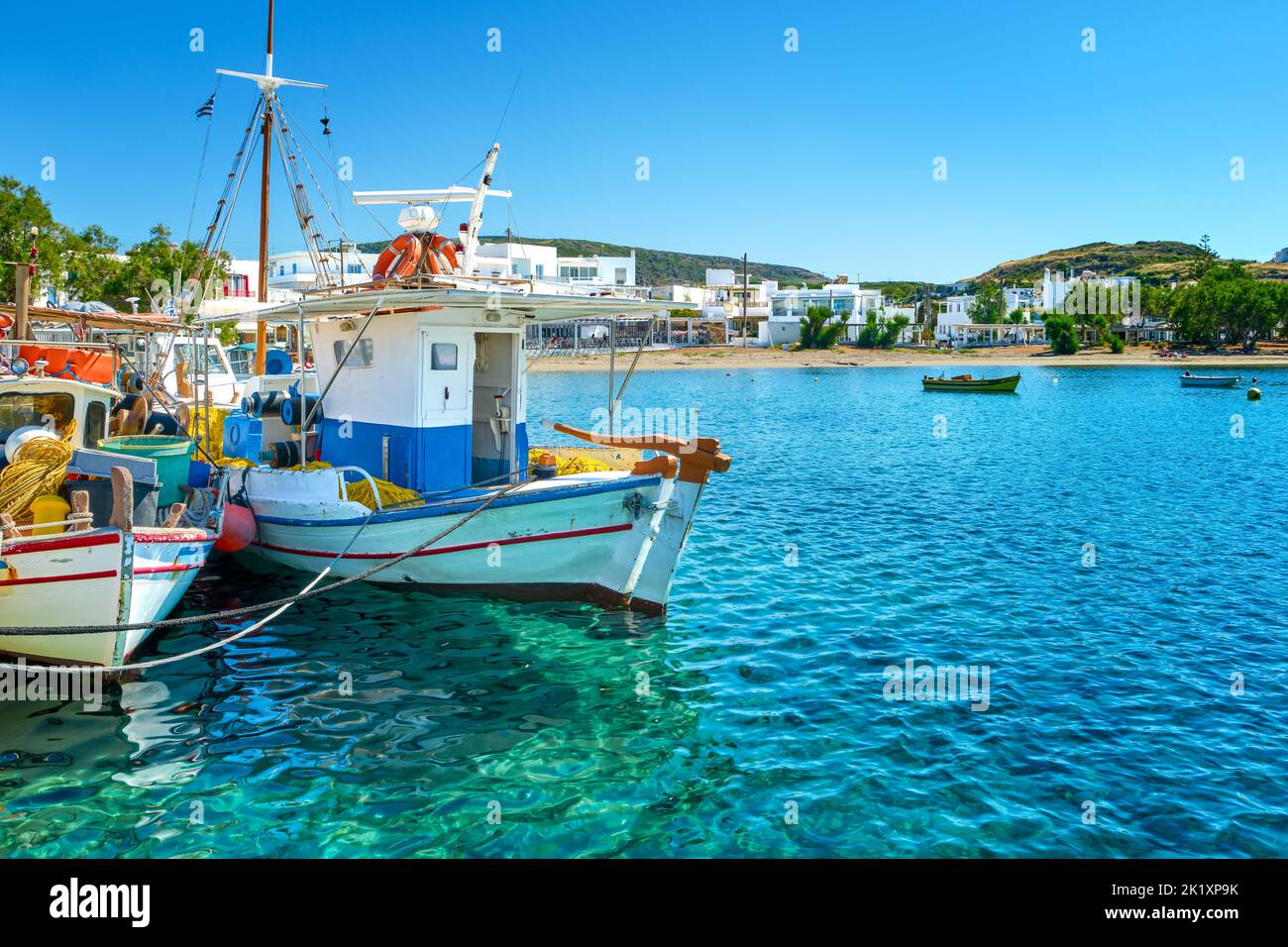 Beautiful view of Greek fishing boats anchored in a small village. Whitewashed houses, fishing boat, clear blue sky, bay, sea, hills. Milos, Greece Stock Photo