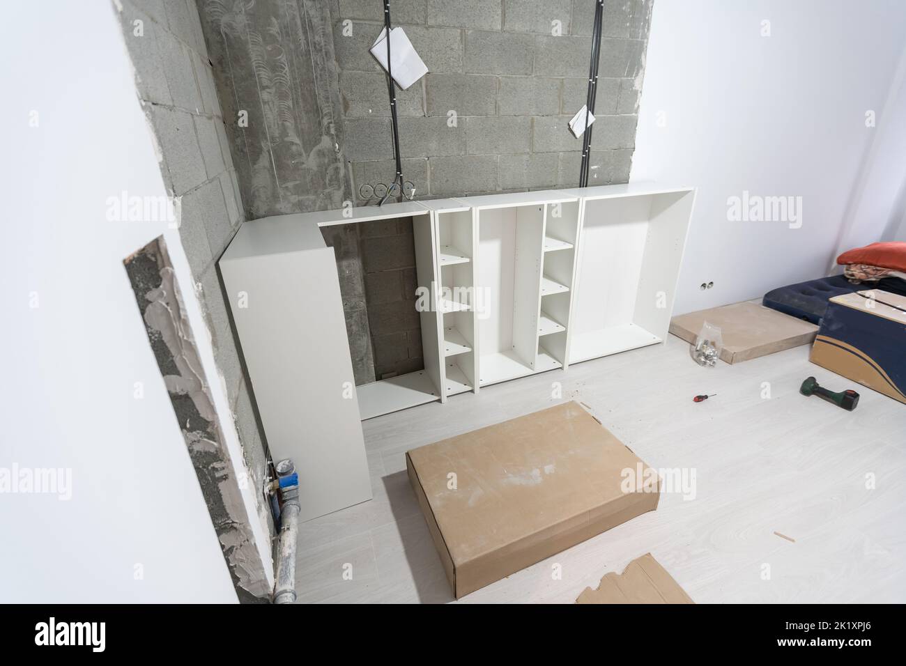 Parts of unfinished furniture, metal screws and tools lying on the ...