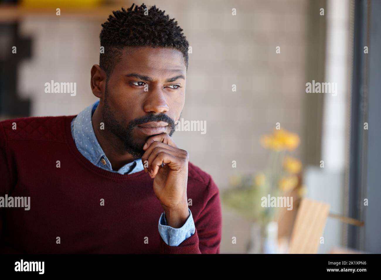 Hes waiting for someone. A young african man sitting in a coffee shop