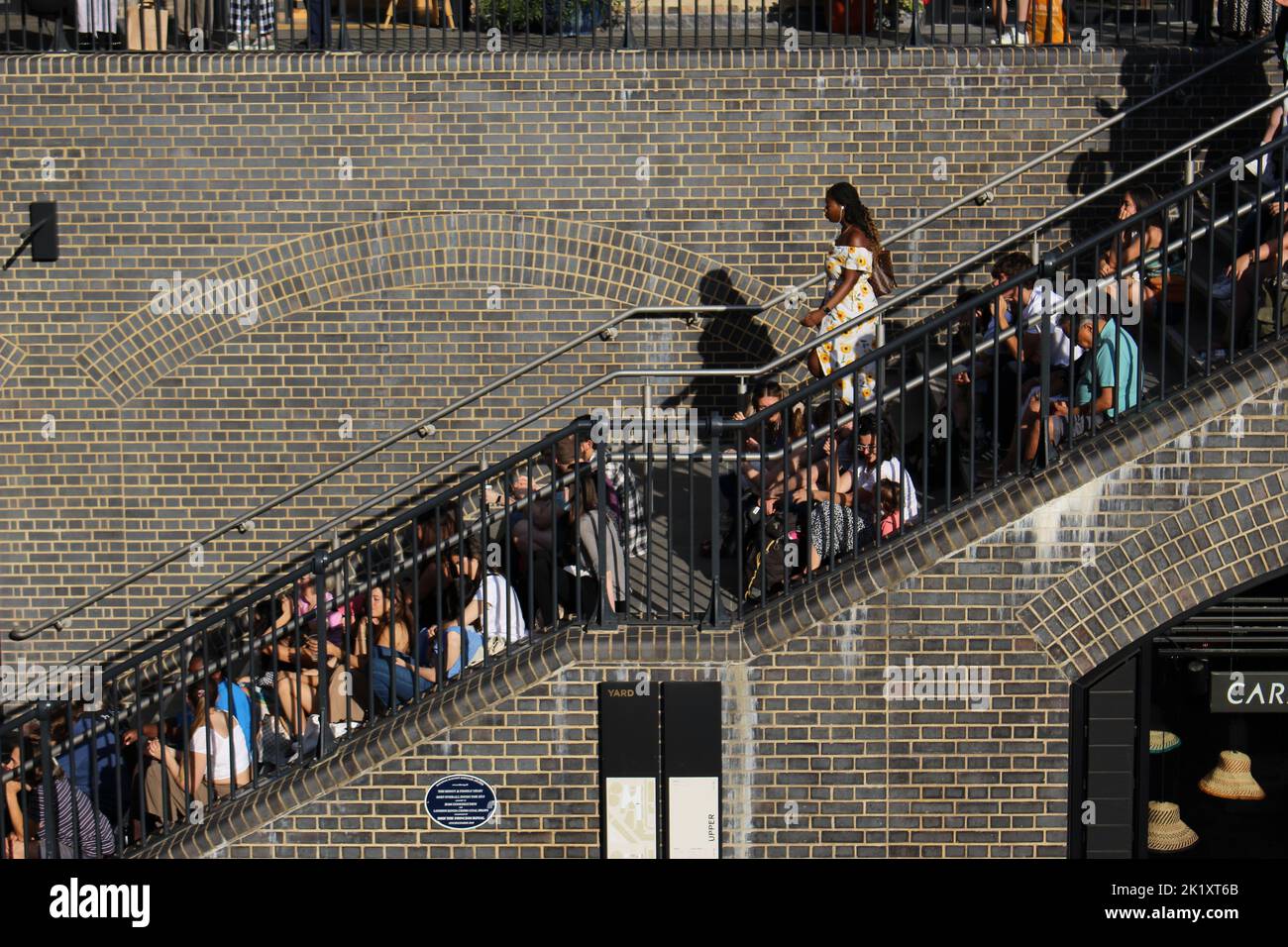 People enjoy a free Kings Cross Summer Sounds festival concert at Coal Drops Yard. Venue was so full people sat on the stairs.Concept for standing out Stock Photo