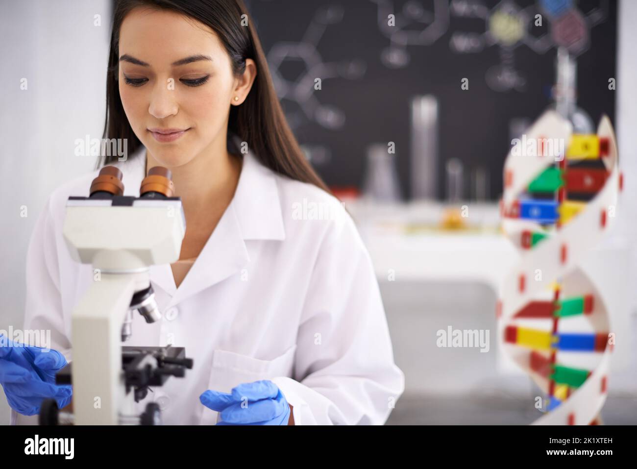 Unlocking the secrets of genetics. Profile of a female scientist viewing a sample through a microscope. Stock Photo
