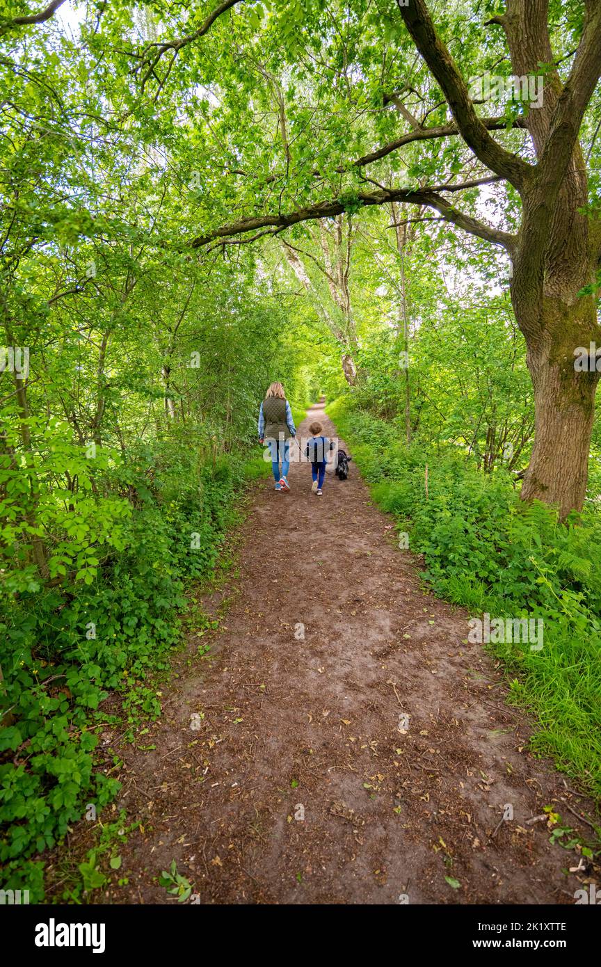 Mother and daughter walking dog asking country path Stock Photo