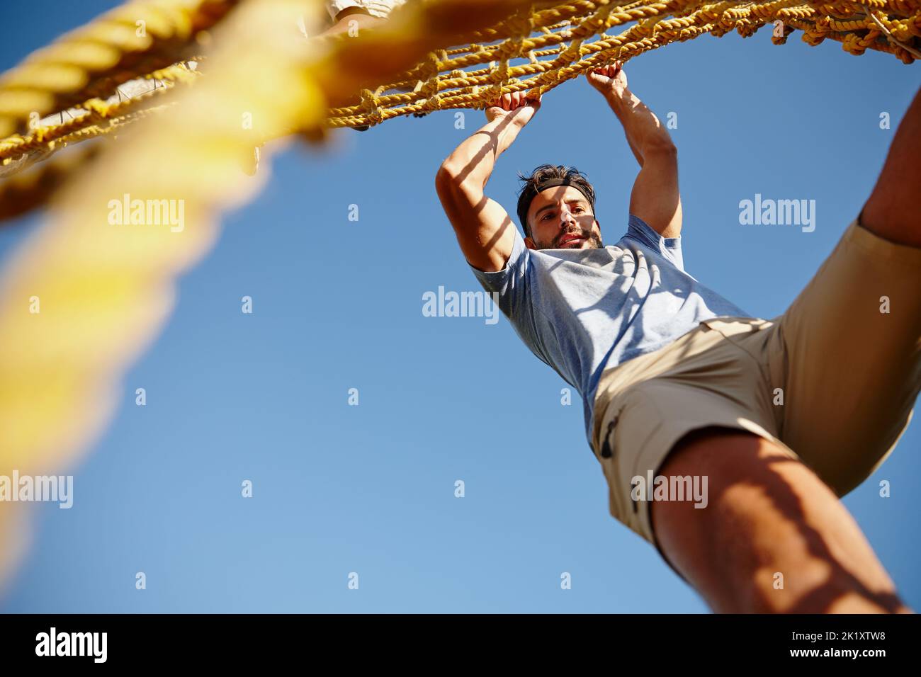 Catch me if you can. a young man gripping a rope wall at bootcamp Stock ...