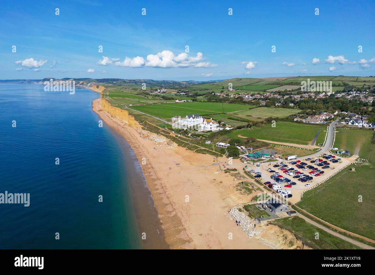 View from the air of the golden sandstone cliffs at hive beach at Burton Bradstock on the Dorset Jurassic coast on a hot sunny autumn day. Stock Photo