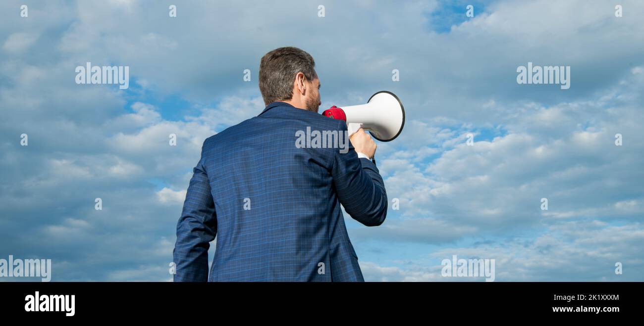 back view of businessman shout in loudspeaker on sky background ...