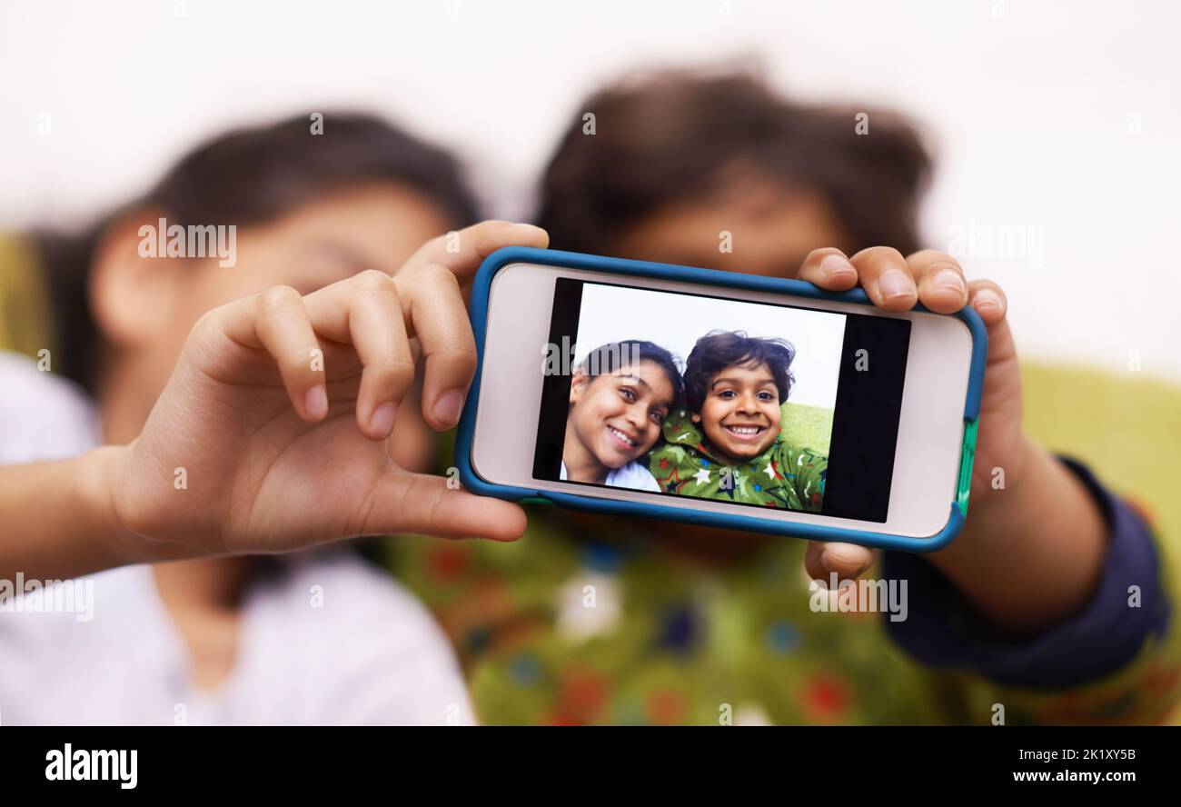 Childhood snapshots. two siblings taking a photo of themselves at home. Stock Photo