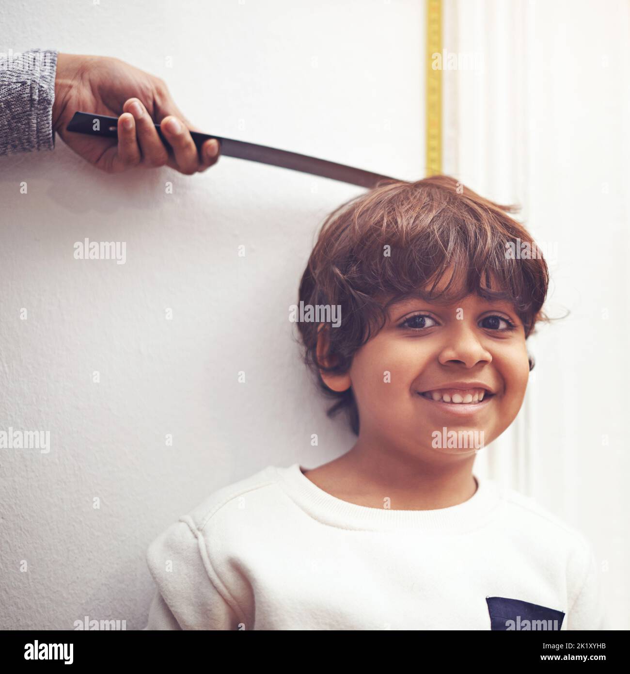 Getting taller every day. a mother measuring how tall her little boy is