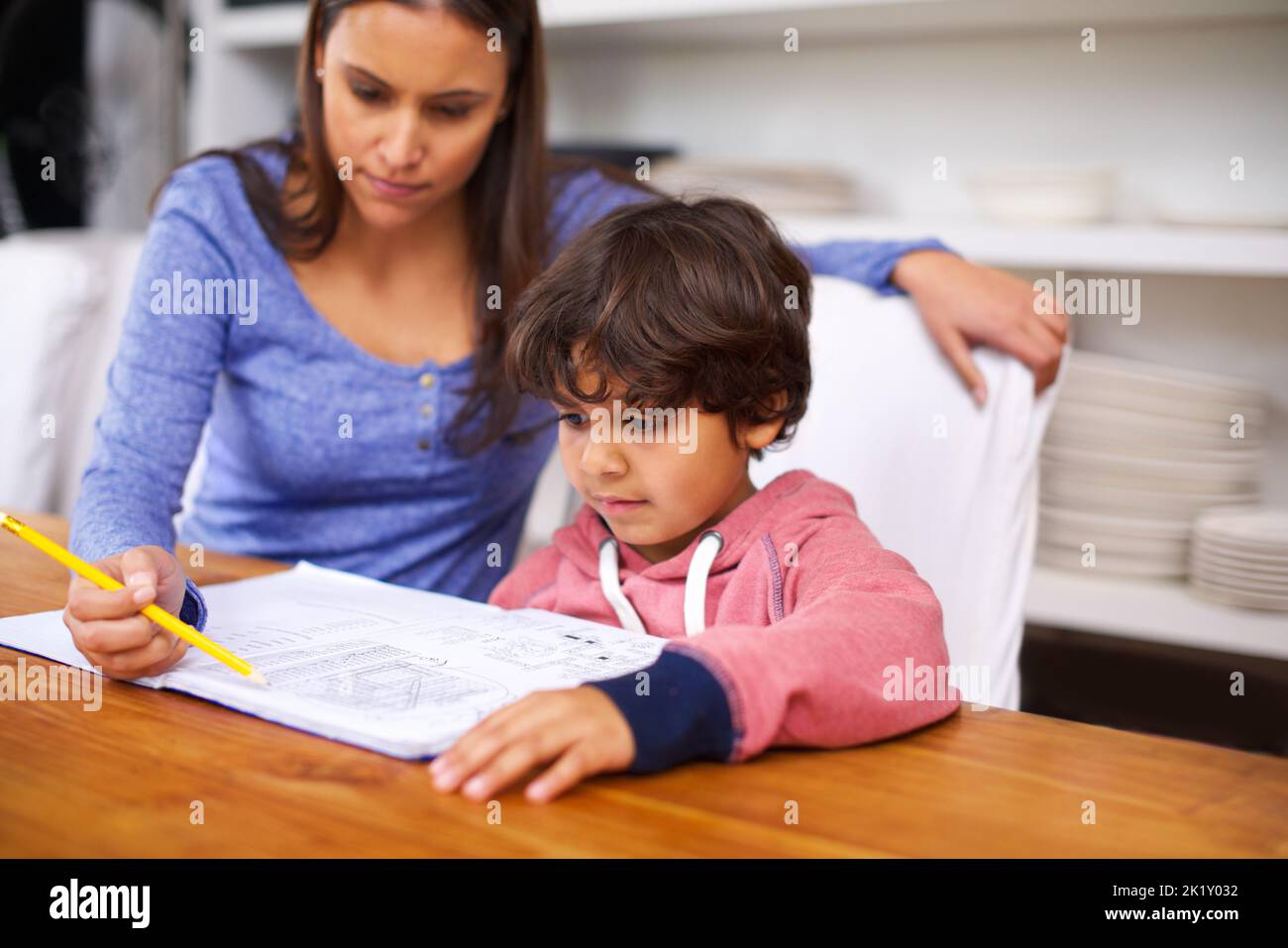 Education starts at home. a mother helping her son with his homework ...