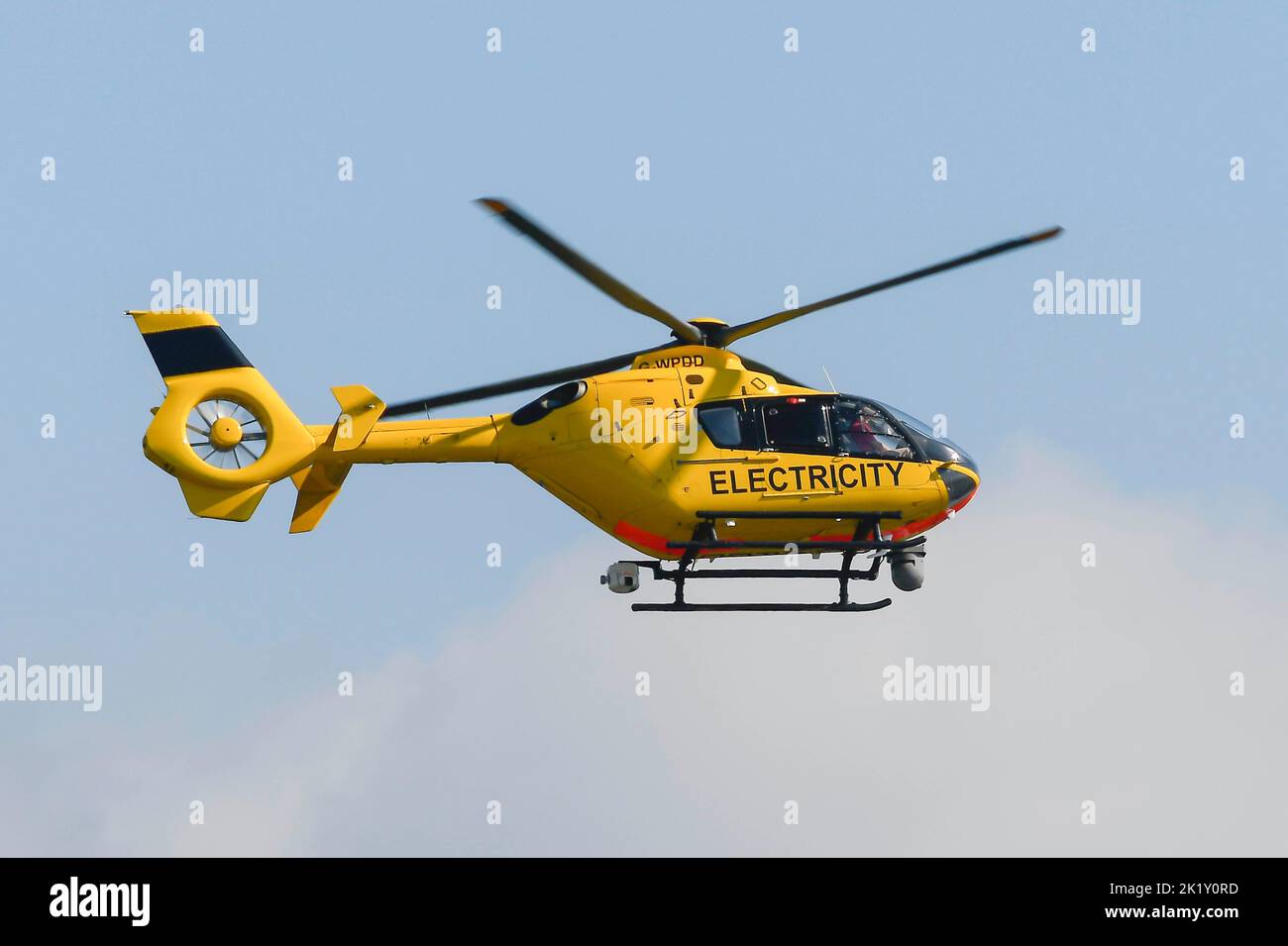 Burton Bradstock, Dorset, UK, 21st September 2022.  A yellow electricity helicopter flying low over electricity power lines checking for faults near houses at Burton Bradstock in Dorset.  Picture Credit: Graham Hunt/Alamy Live News Stock Photo