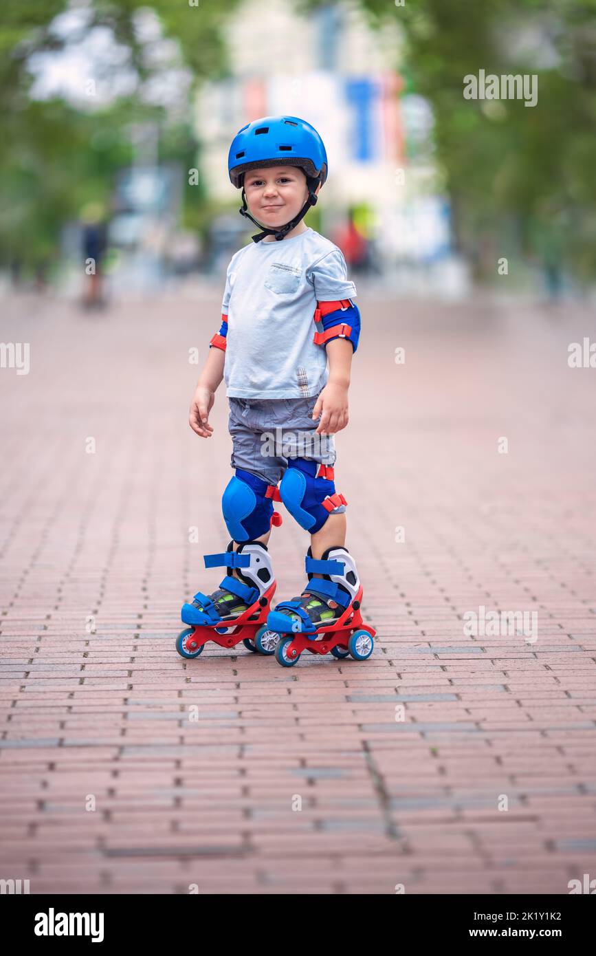 Little baby boy riding roller skates. Kid with helmet and protection on roller blades. Roller skating. Varna Stock Photo