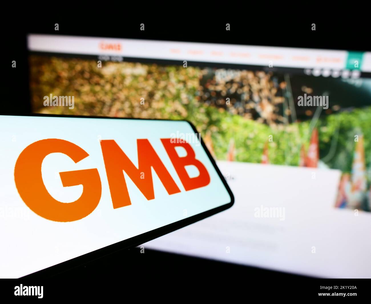 Mobile phone with logo of British trade union GMB on screen in front of website. Focus on left of phone display. Stock Photo