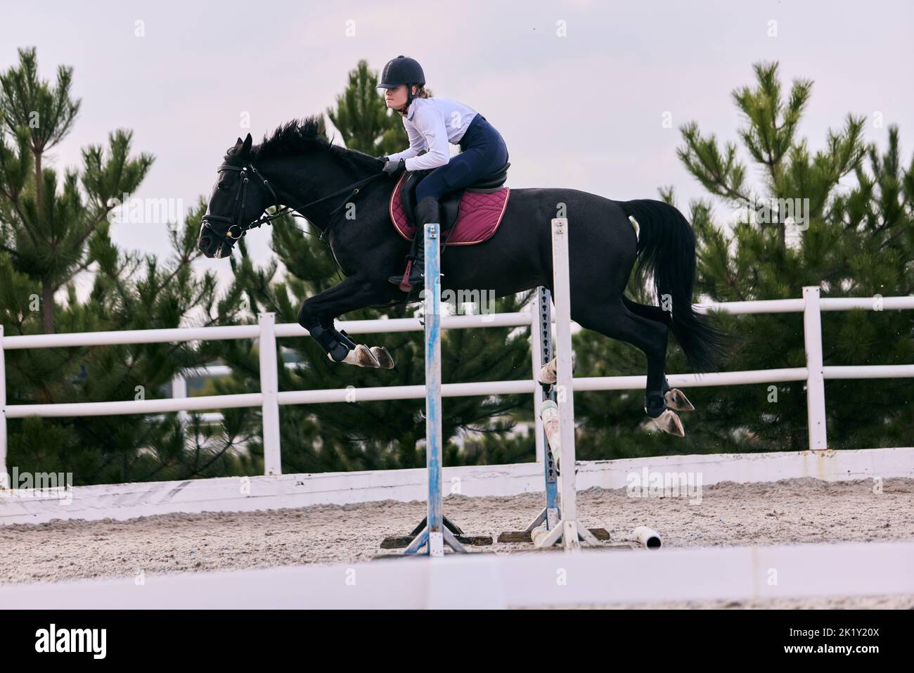 Equestrian sport. Portrait of young woman training at riding arena in