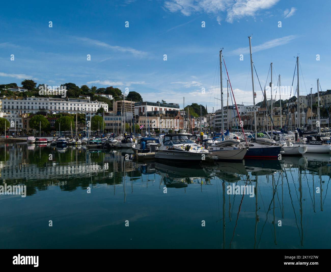 View across Torquay Marina with expensive leisurecraft moored and whitewashed sea front properties Devon England UK Stock Photo