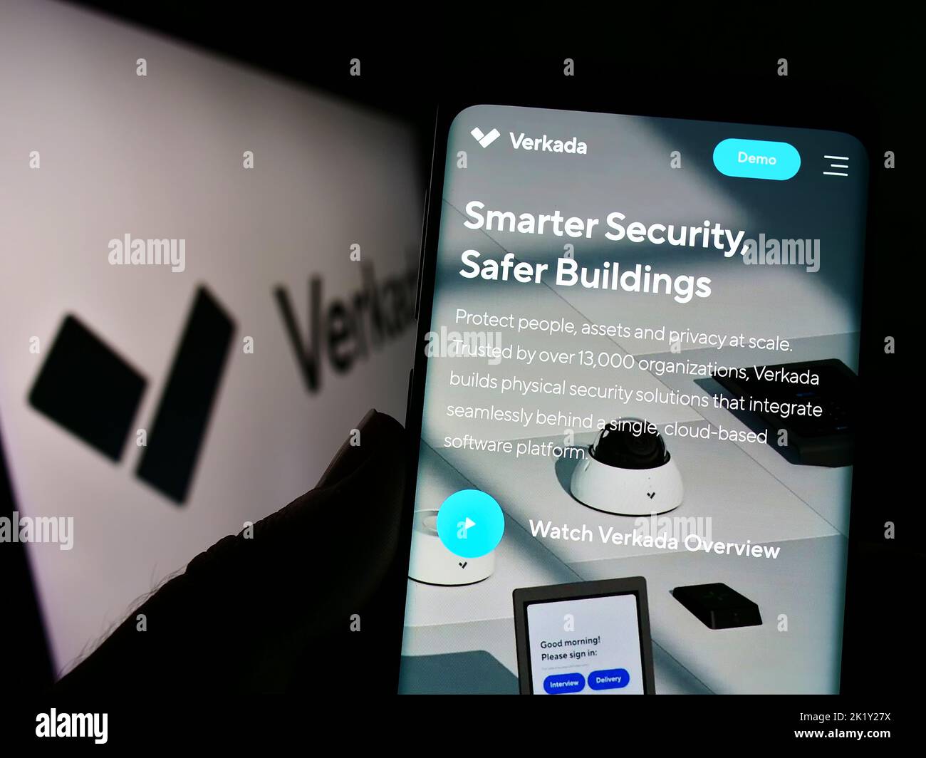 Person holding cellphone with website of US security systems company Verkada Inc. on screen in front of logo. Focus on center of phone display. Stock Photo