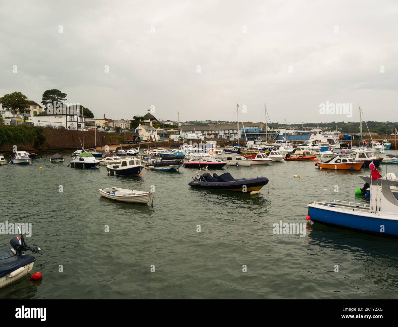 View across Paignton harbour to Harbour Light Hotel with moored leisurecraft on a grey rainy day Devon England UK Stock Photo