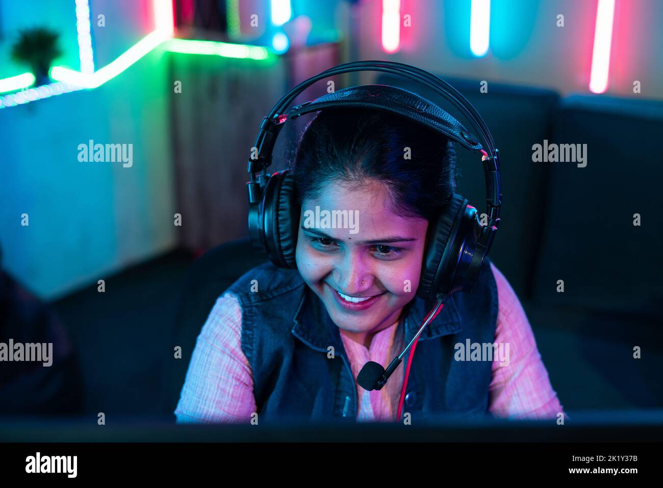 top of happy girl playing online live video game on computer by talking on headphone at home - concept of social media sharing, internet and vlogging Stock Photo